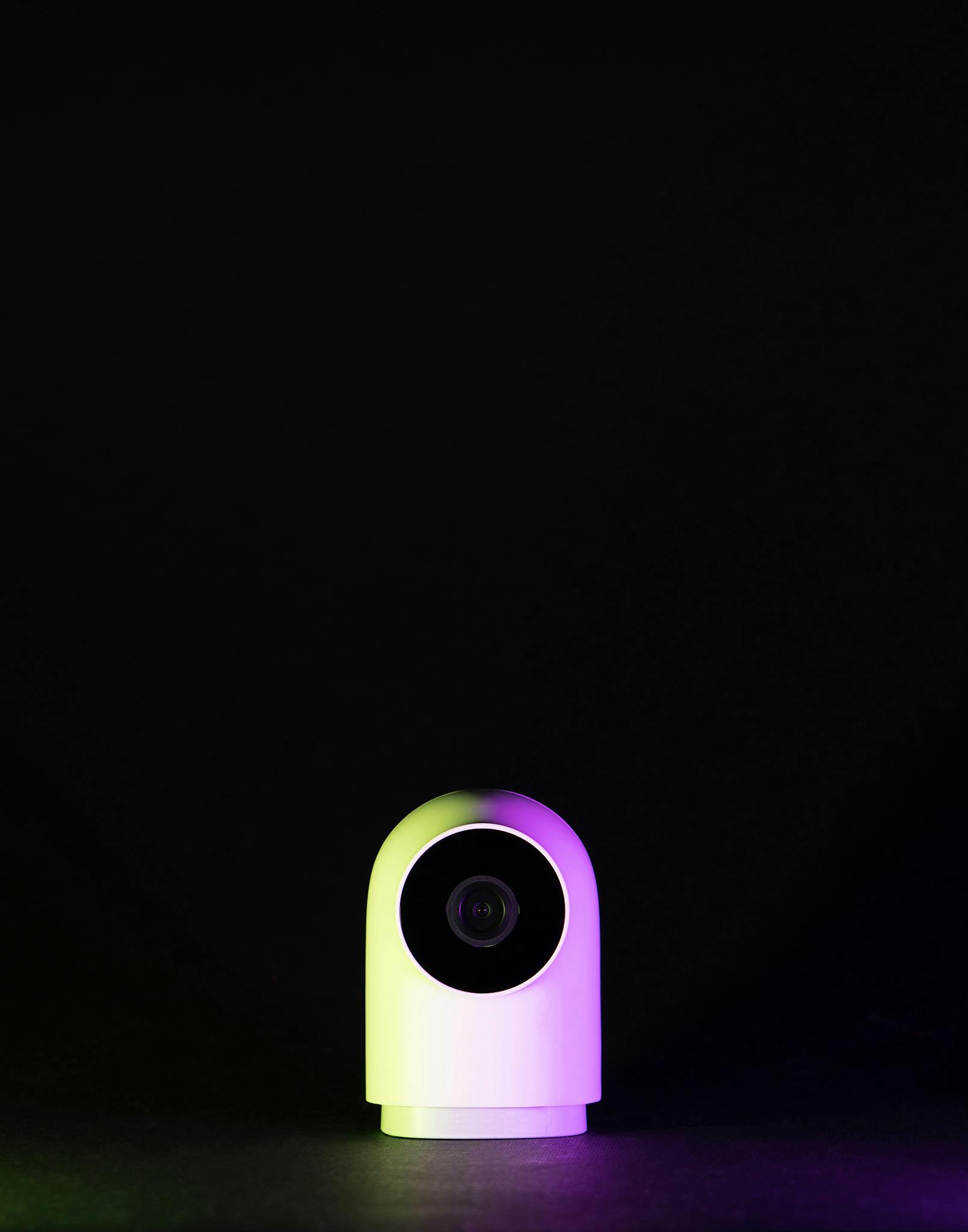 Sleek white webcam on a black background with neon lighting, emphasizing technology and modern design.